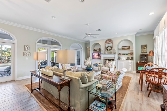 living room with crown molding, light hardwood / wood-style flooring, ceiling fan, and built in features