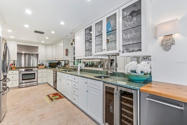 kitchen featuring sink, white cabinets, stainless steel appliances, and range hood