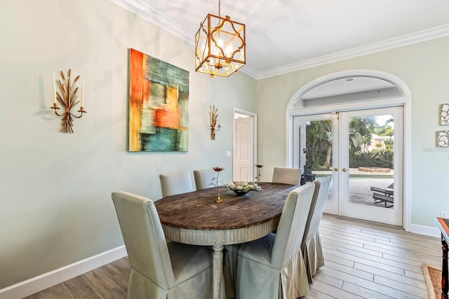 dining area featuring hardwood / wood-style floors, an inviting chandelier, ornamental molding, and french doors