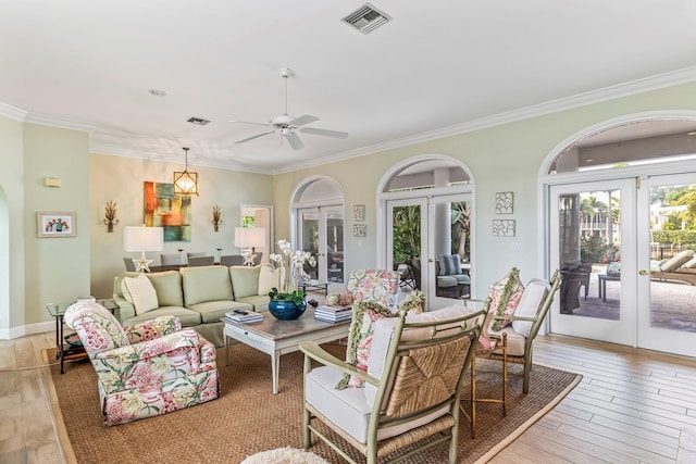 living room with light hardwood / wood-style floors, ornamental molding, and french doors