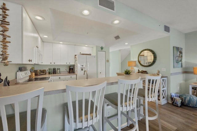 kitchen featuring kitchen peninsula, white appliances, sink, light hardwood / wood-style flooring, and white cabinetry