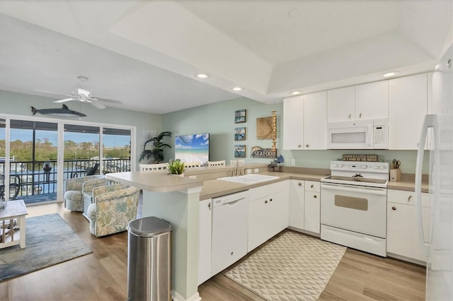 kitchen featuring kitchen peninsula, white appliances, light hardwood / wood-style floors, and sink