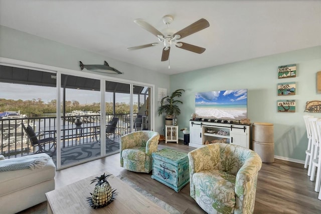 living room with a ceiling fan, baseboards, and wood finished floors