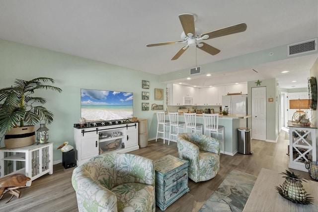 living room with a ceiling fan, baseboards, visible vents, and wood finished floors