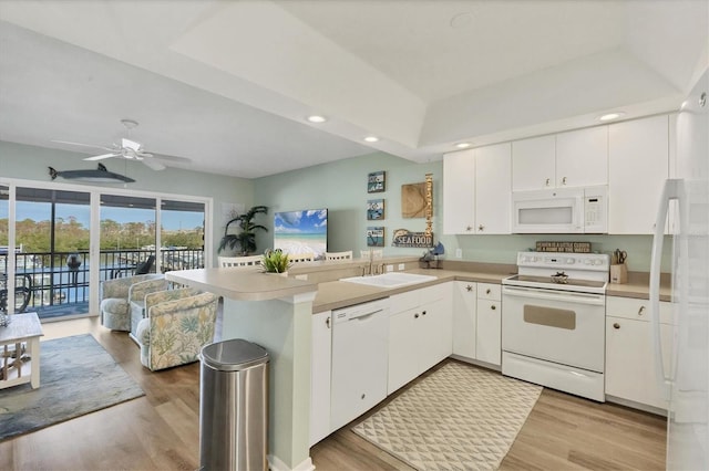 kitchen with a ceiling fan, a sink, a peninsula, open floor plan, and white appliances