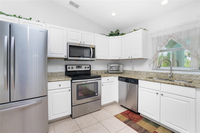 kitchen featuring vaulted ceiling, white cabinetry, appliances with stainless steel finishes, and sink