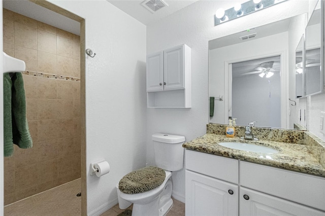 bathroom with vanity, ceiling fan, toilet, and tiled shower