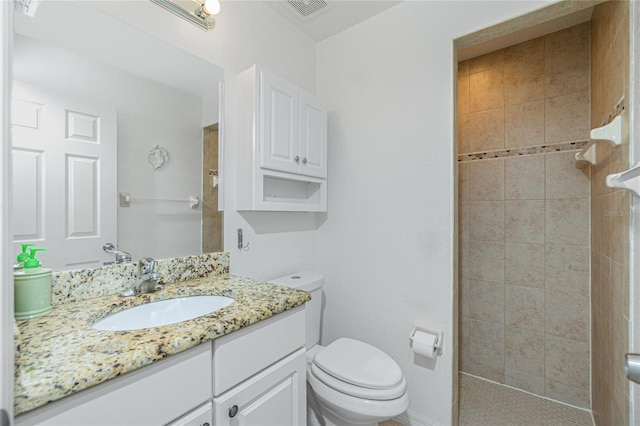 bathroom featuring vanity, toilet, and tiled shower