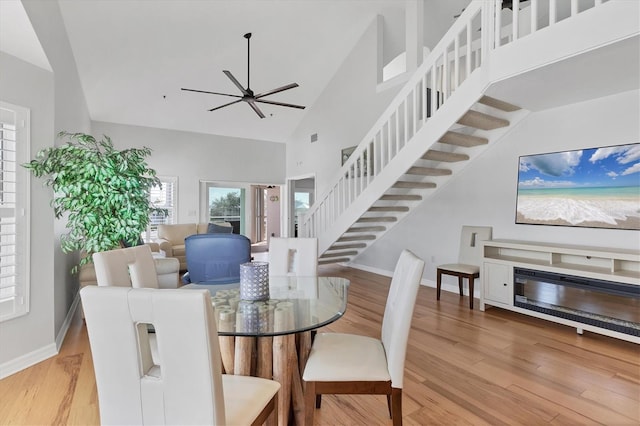 dining room featuring light wood-type flooring, high vaulted ceiling, and ceiling fan