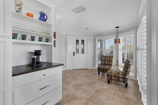 interior space featuring white cabinetry, hanging light fixtures, and ornamental molding