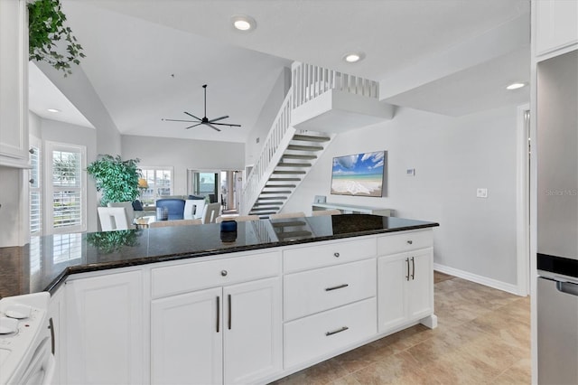 kitchen with white cabinetry, dark stone countertops, stainless steel refrigerator, vaulted ceiling, and ceiling fan