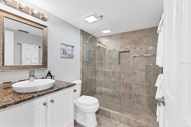 bathroom featuring vanity, toilet, tile patterned floors, and a shower with shower door