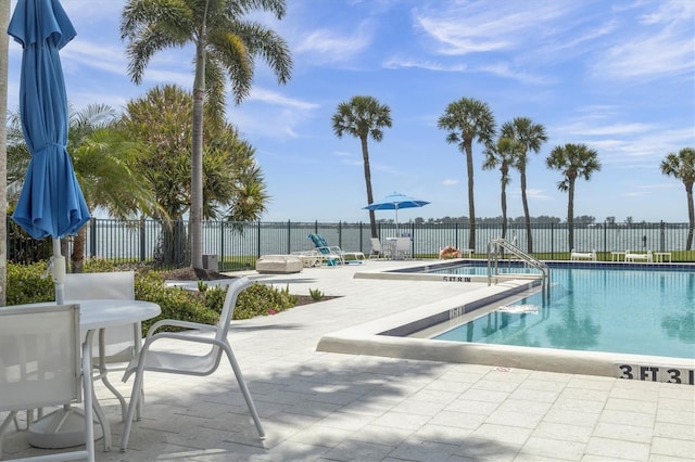 view of swimming pool featuring a patio area and a water view