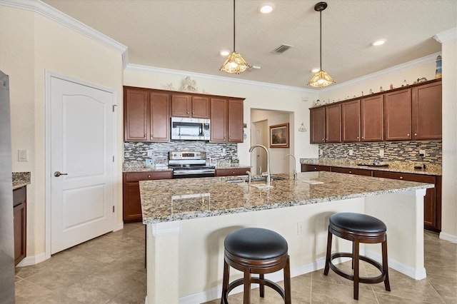 kitchen with sink, hanging light fixtures, stainless steel appliances, crown molding, and an island with sink