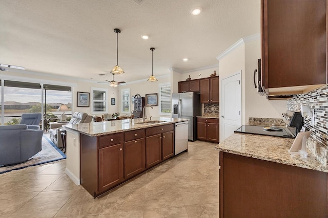 kitchen featuring appliances with stainless steel finishes, tasteful backsplash, ceiling fan, a kitchen island with sink, and decorative light fixtures