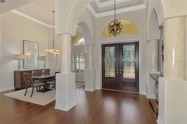 entryway featuring french doors, dark hardwood / wood-style floors, decorative columns, a towering ceiling, and ornamental molding