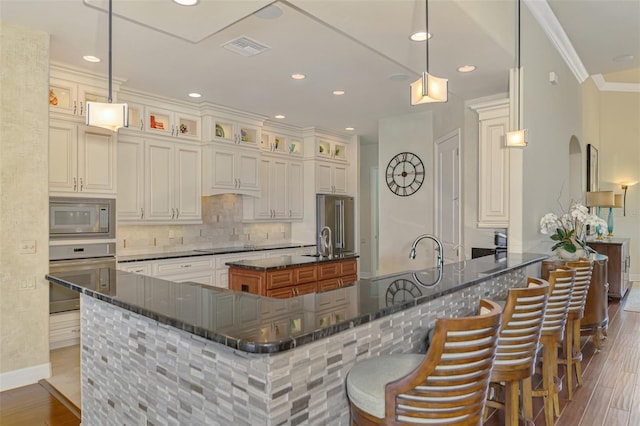 kitchen with backsplash, a breakfast bar, stainless steel appliances, and decorative light fixtures