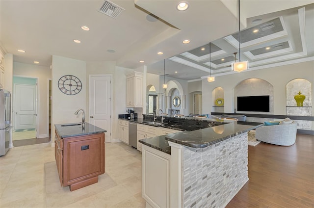 kitchen with coffered ceiling, sink, decorative light fixtures, appliances with stainless steel finishes, and a large island