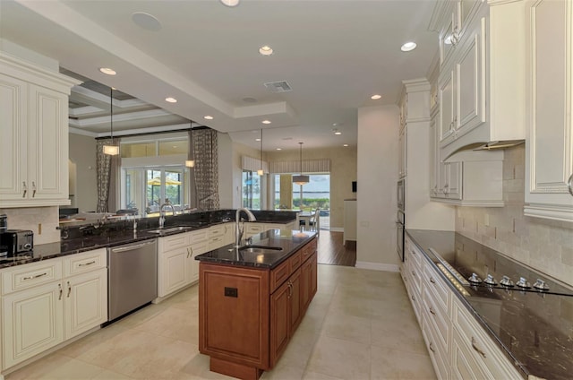 kitchen with pendant lighting, appliances with stainless steel finishes, dark stone counters, and sink