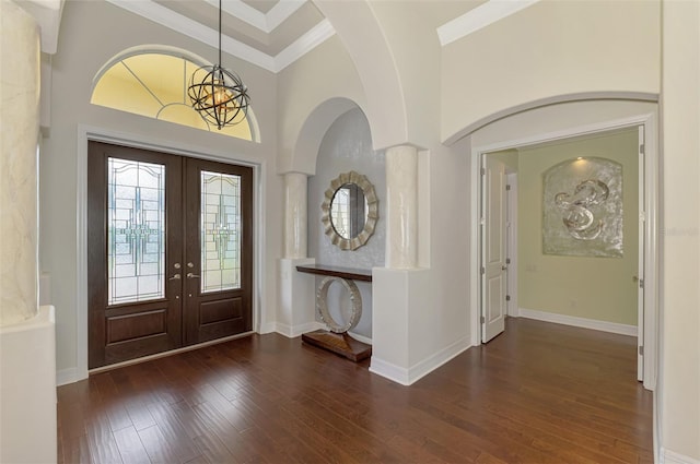 foyer entrance with a towering ceiling, crown molding, dark wood-type flooring, and french doors