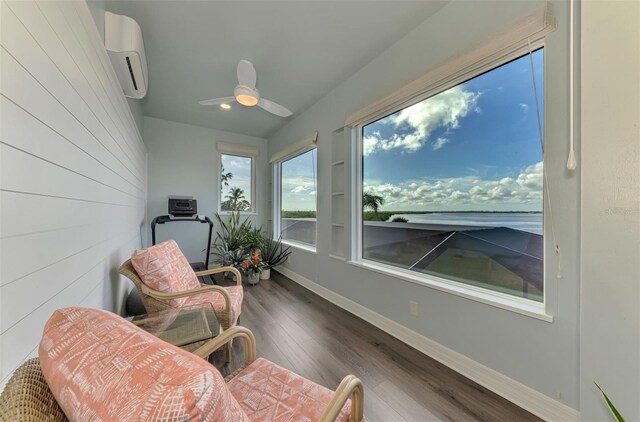 living area featuring hardwood / wood-style flooring, an AC wall unit, and ceiling fan