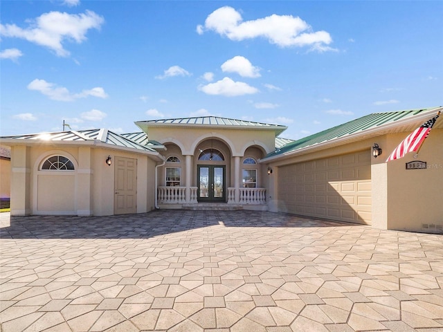 view of front of house featuring a garage, covered porch, and french doors