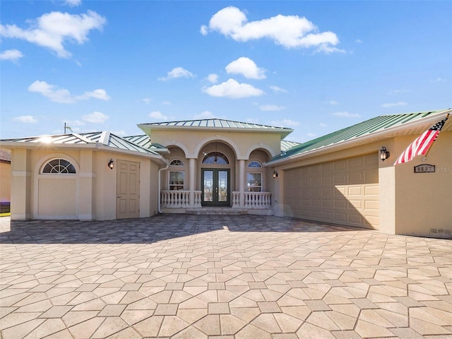 9567 Honeymoon Dr, Port Charlotte, FL 33981 - mediterranean / spanish-style home with french doors, a standing seam roof, stucco siding, a metal roof, and decorative driveway