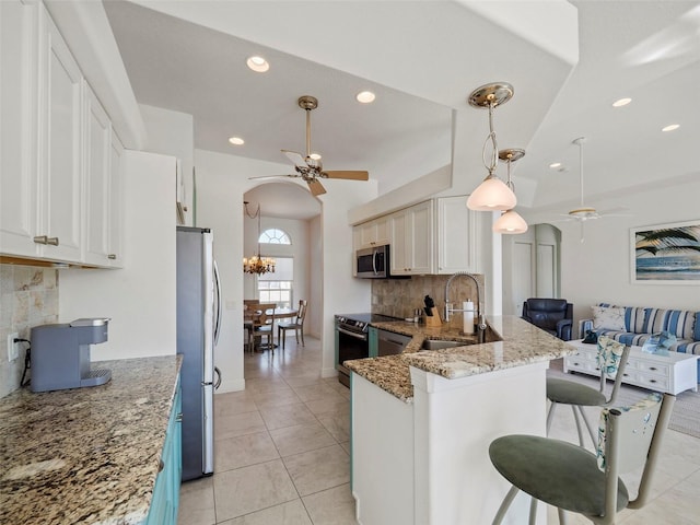 kitchen with kitchen peninsula, backsplash, stainless steel appliances, sink, and white cabinets