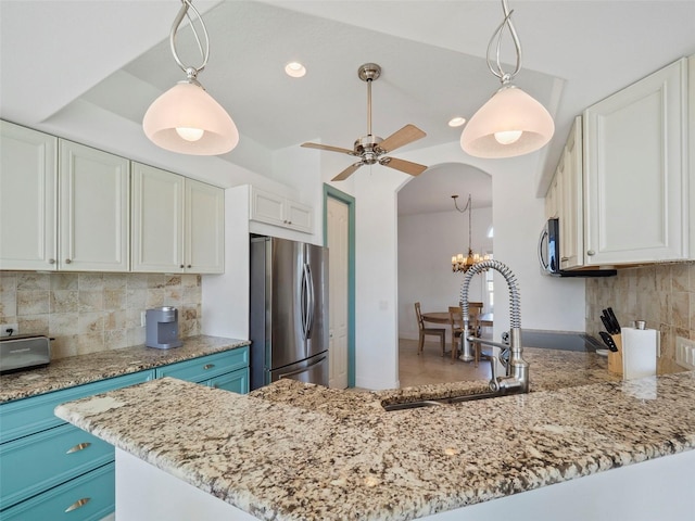 9567 Honeymoon Dr, Port Charlotte, FL 33981 - kitchen featuring freestanding refrigerator, white cabinetry, light stone counters, tasteful backsplash, and a peninsula