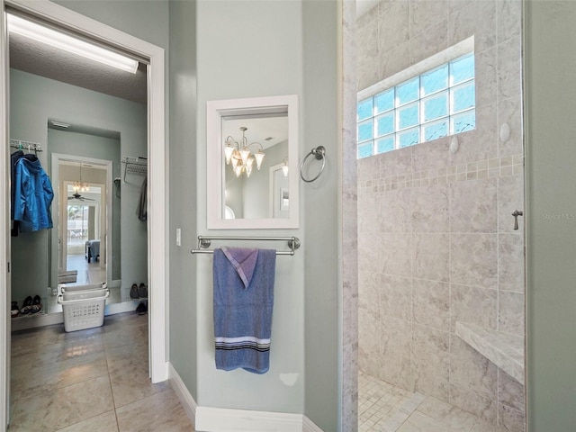 bathroom with tiled shower, ceiling fan with notable chandelier, and tile patterned floors