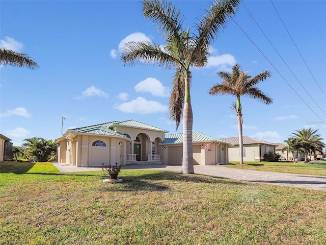 9567 Honeymoon Dr, Port Charlotte, FL 33981 - mediterranean / spanish-style home with a standing seam roof, a garage, decorative driveway, a front lawn, and a metal roof
