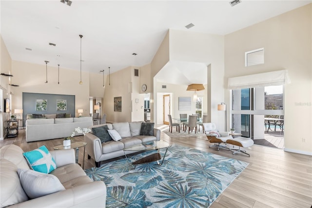 living room with light wood-type flooring and a towering ceiling