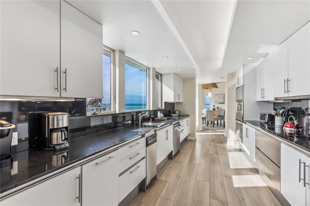 kitchen with dishwasher, light wood-type flooring, tasteful backsplash, and white cabinetry