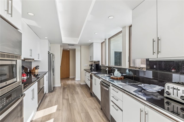 kitchen featuring white cabinets, sink, light wood-type flooring, and stainless steel appliances