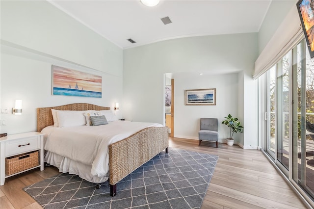 bedroom with access to exterior, wood-type flooring, and vaulted ceiling