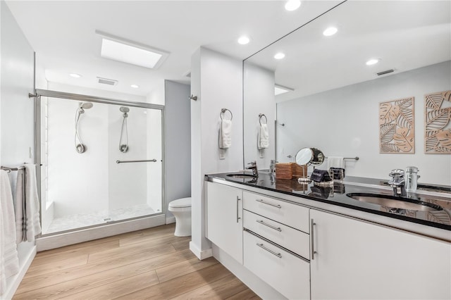 bathroom featuring wood-type flooring, vanity, toilet, and a shower with door