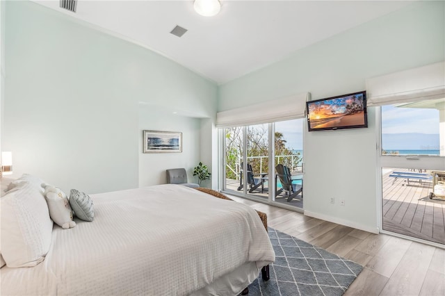 bedroom with access to exterior, hardwood / wood-style floors, and lofted ceiling