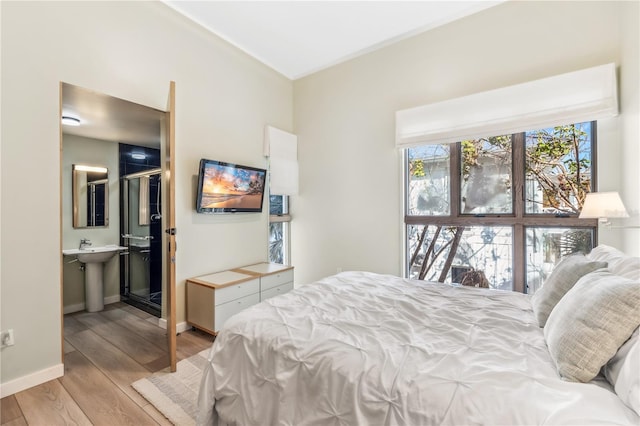 bedroom featuring ensuite bathroom, light hardwood / wood-style floors, and sink