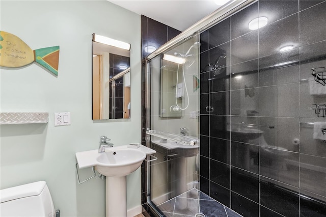 bathroom with toilet, a shower with shower door, and sink