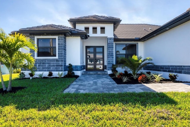 entrance to property featuring a lawn and french doors