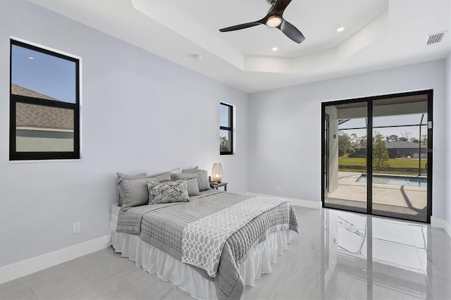 bedroom featuring ceiling fan, access to exterior, and a tray ceiling