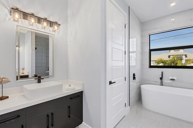 bathroom featuring a tub to relax in, vanity, and tile walls