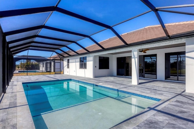 view of swimming pool with ceiling fan, a patio area, and glass enclosure