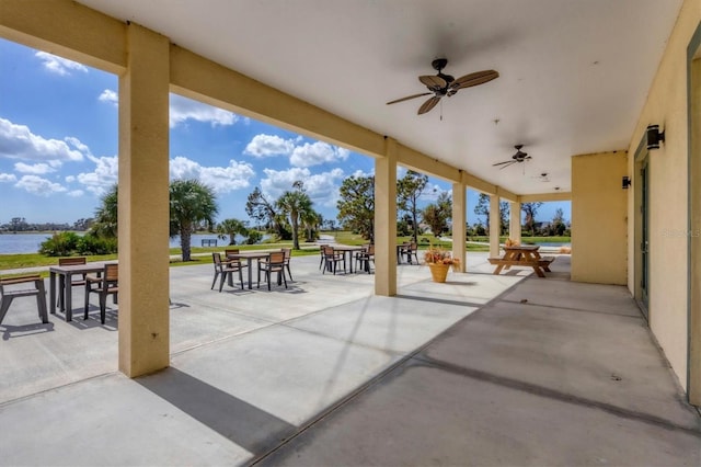 view of patio with a water view and ceiling fan