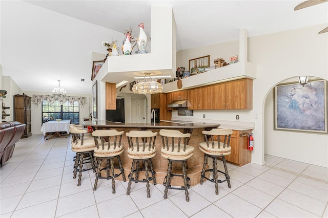 kitchen featuring kitchen peninsula, light tile patterned floors, a breakfast bar, and extractor fan