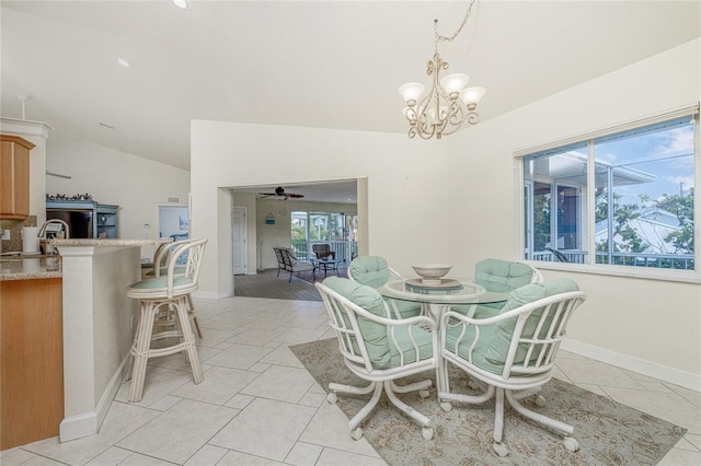 tiled dining area featuring ceiling fan with notable chandelier and lofted ceiling