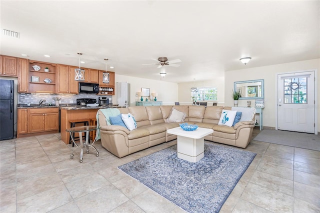 living room with ceiling fan, a healthy amount of sunlight, light tile patterned floors, and sink