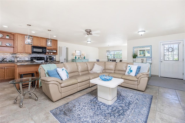 tiled living room with plenty of natural light, ceiling fan, and sink