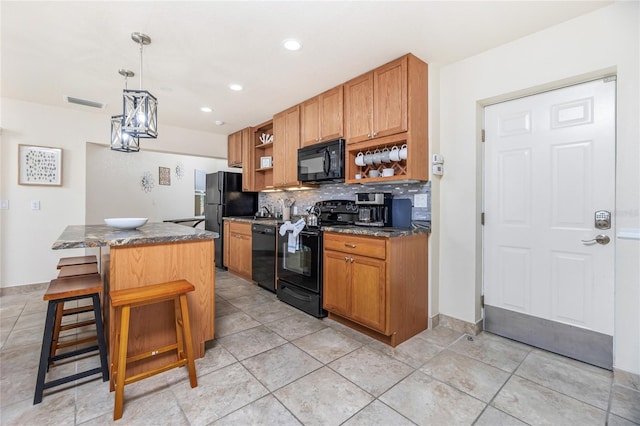 kitchen with pendant lighting, a breakfast bar area, decorative backsplash, a kitchen island, and black appliances