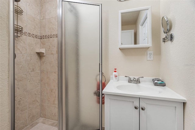 bathroom featuring a shower with door and vanity